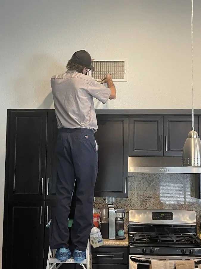 Technician inspecting an air vent during HVAC service in Blendon